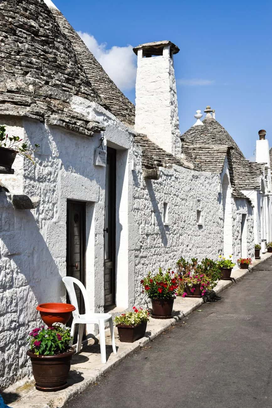 Ruelle calme de trulli habités avec pots de fleurs à Alberobello
