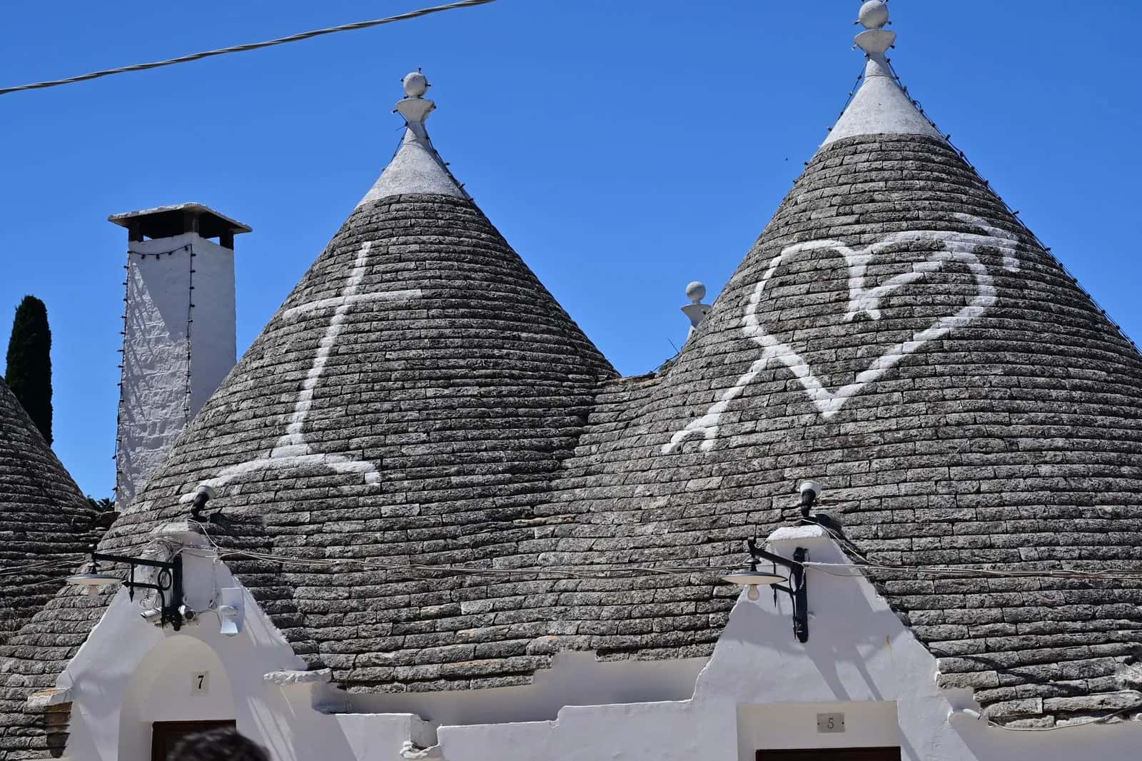 Gros plan sur des toits coniques de trulli ornés de symboles peints à la chaux et de pinacles à Alberobello