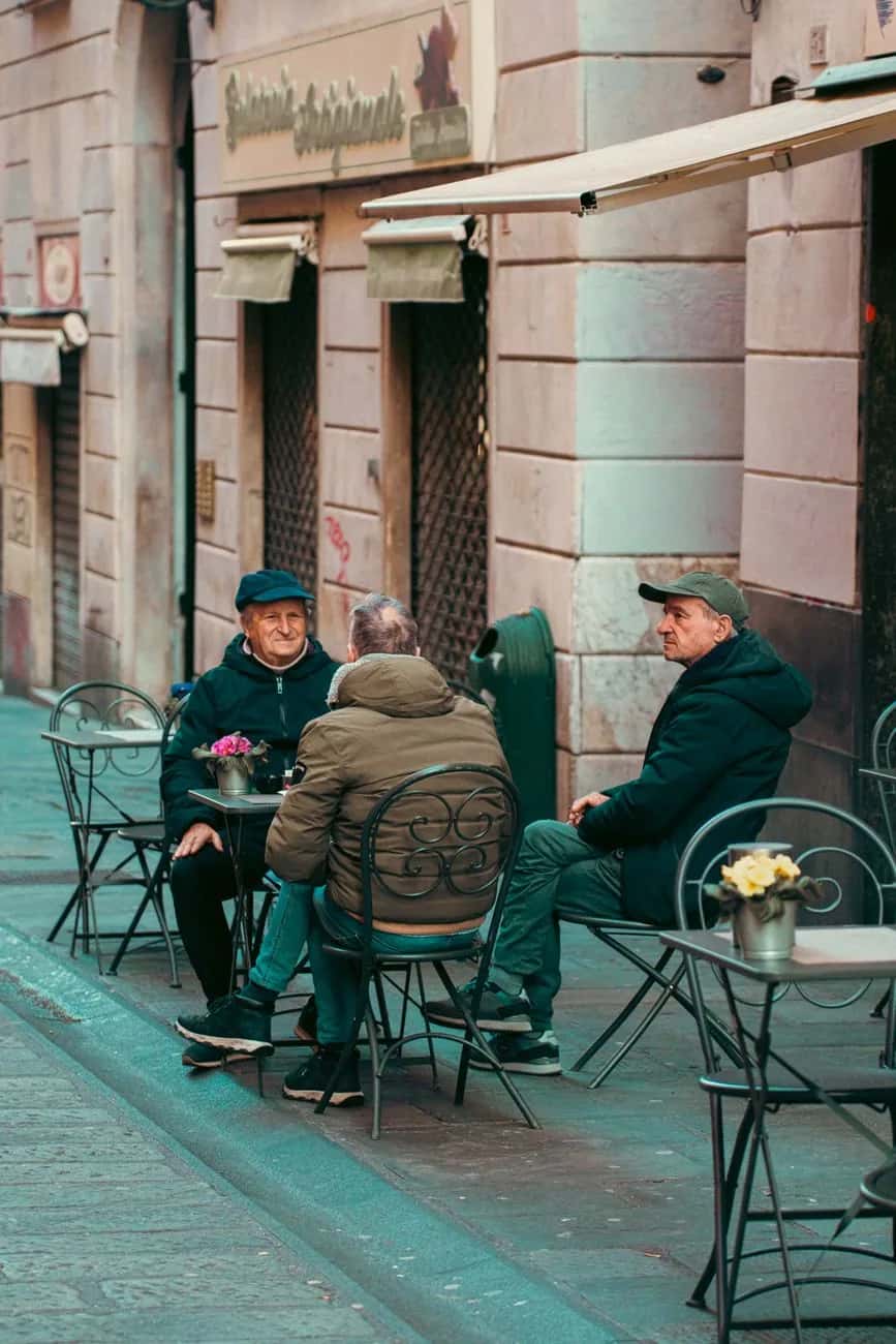Trois habitants discutent à la terrasse d'un café dans le centre historique de Gênes