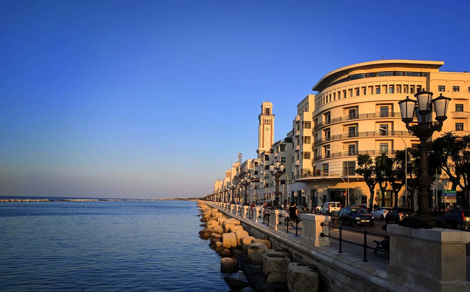Le lungomare de Bari au coucher du soleil, avec ses lampadaires, ses palmiers et les immeubles du front de mer