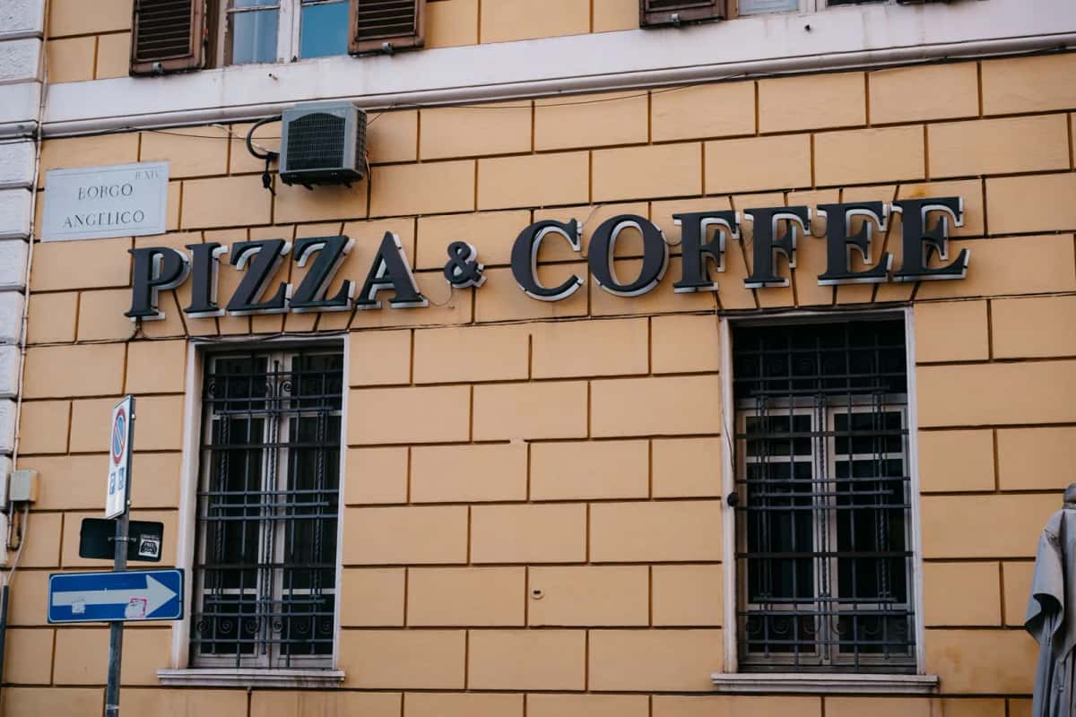 Enseigne Pizza & Coffee sur une façade ocre du Borgo Angelico, près du Vatican, à Rome en Italie