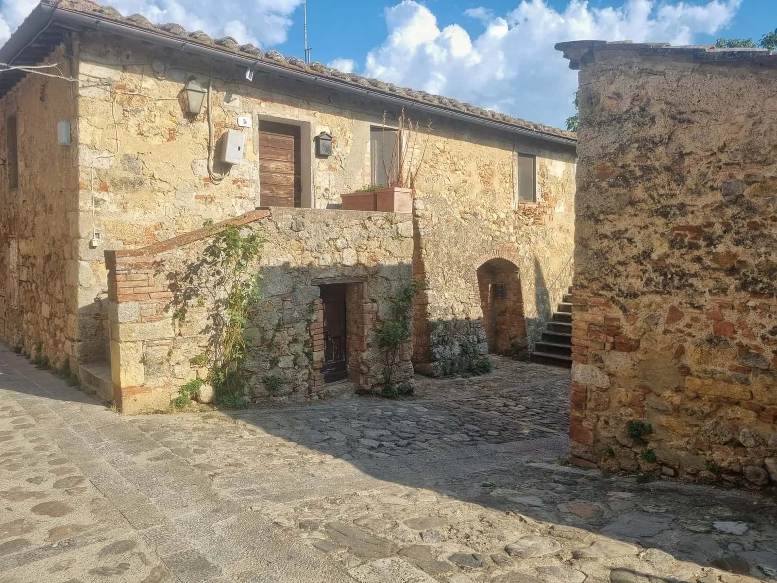 Maisons en pierre et ruelle pavée dans un village médiéval de Toscane