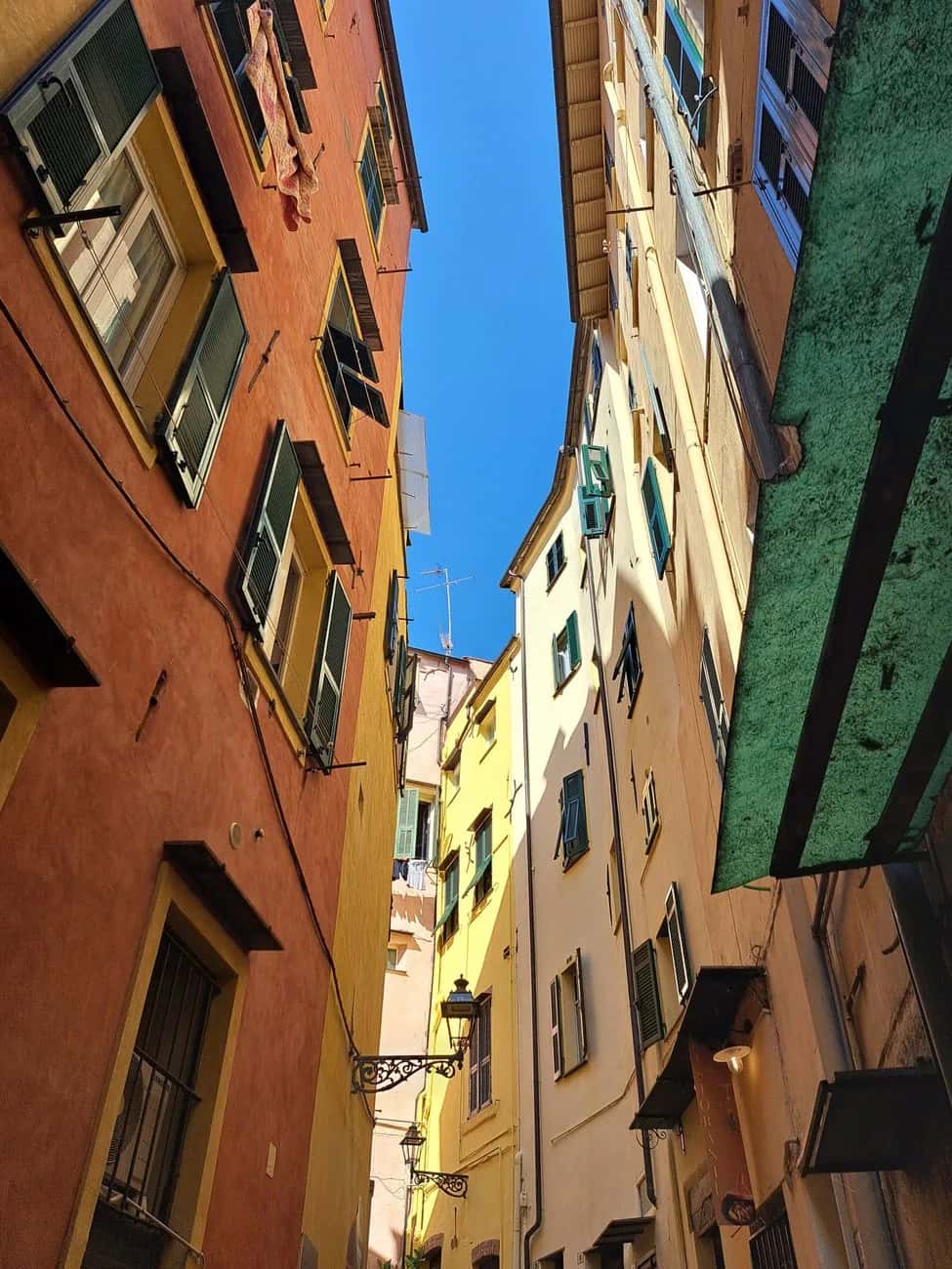 Ruelle étroite bordée de façades ocre et jaunes dans la vieille ville de Sanremo, en Ligurie