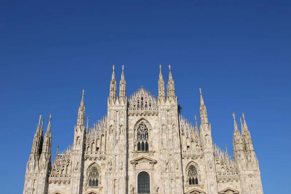 La façade gothique en marbre blanc du Duomo de Milan, cathédrale emblématique de la Lombardie, sous un ciel bleu
