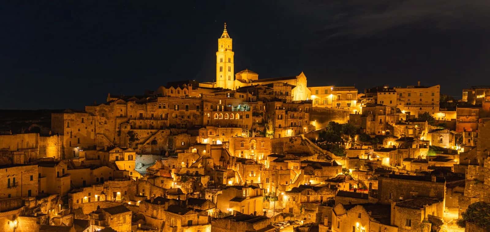 Les Sassi de Matera illuminés la nuit, avec le campanile de la cathédrale dominant les habitations troglodytes