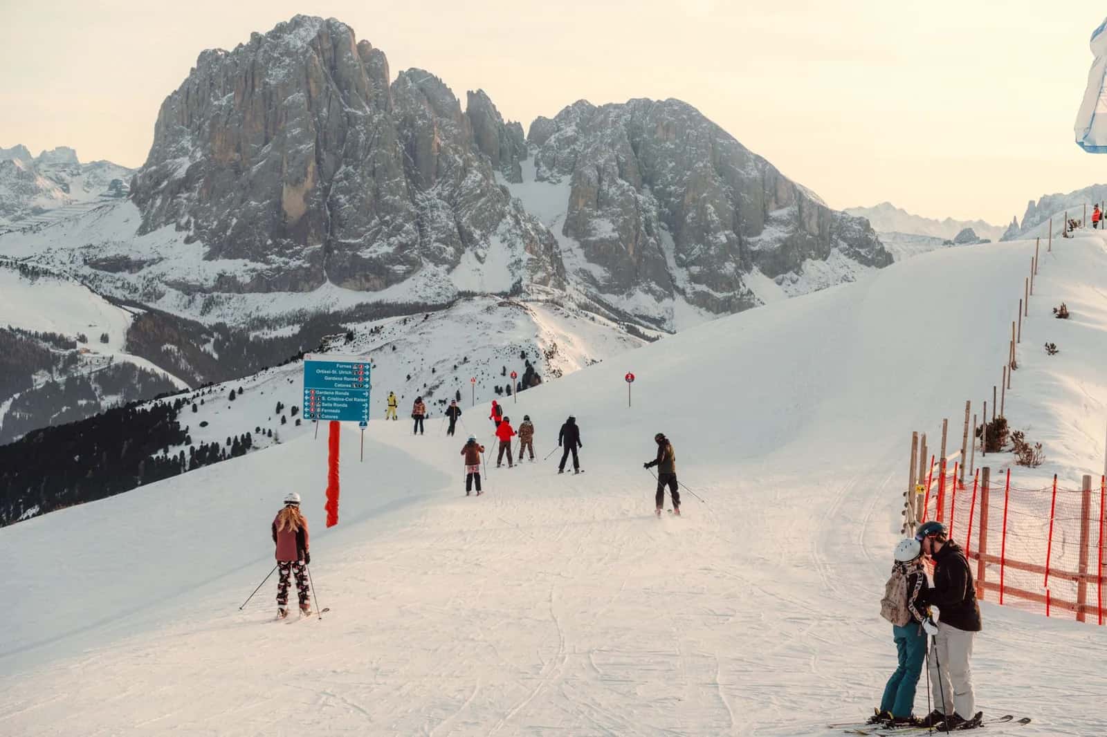 Skieurs sur une piste enneigée au pied des sommets rocheux des Dolomites