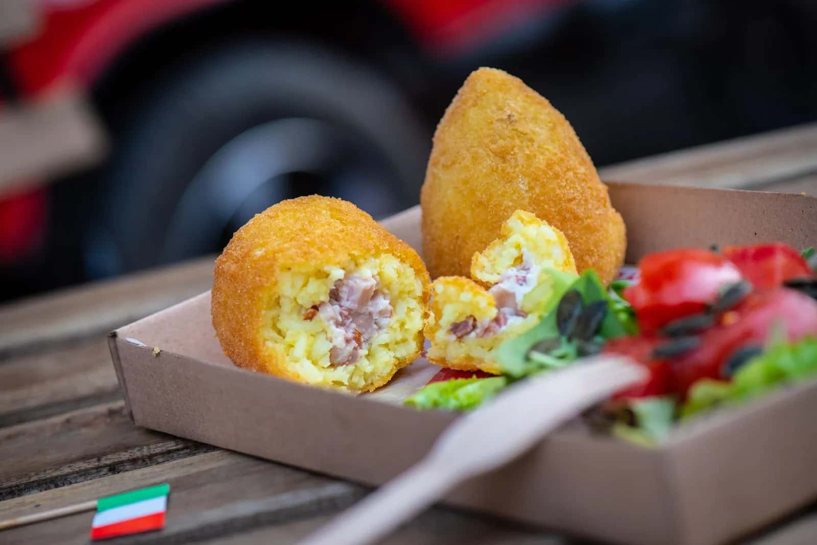 Arancina sicilienne ouverte en deux dans une barquette, la boule de riz safrané frite emblématique de Palerme