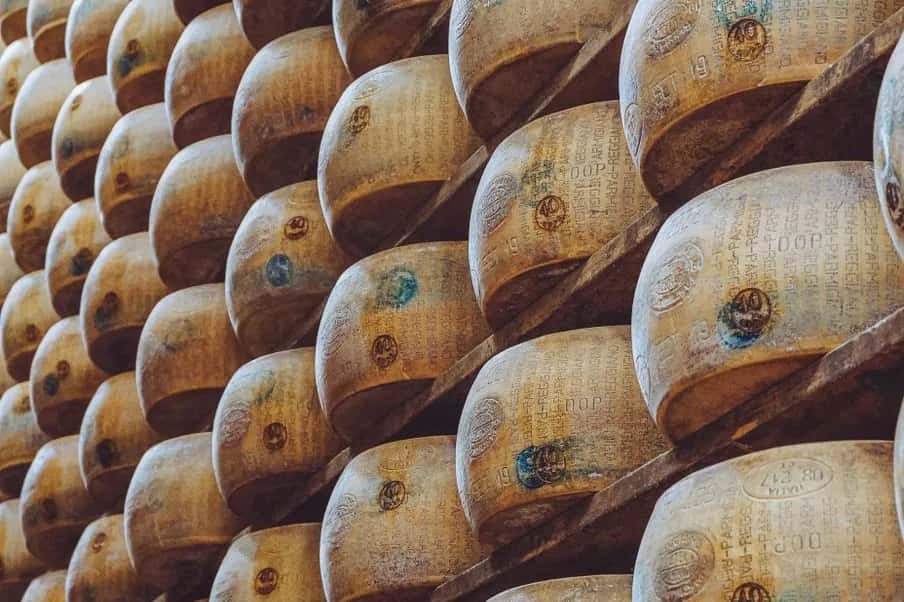 Meules de parmigiano reggiano alignées sur des étagères en bois dans une cave d'affinage d'Émilie-Romagne