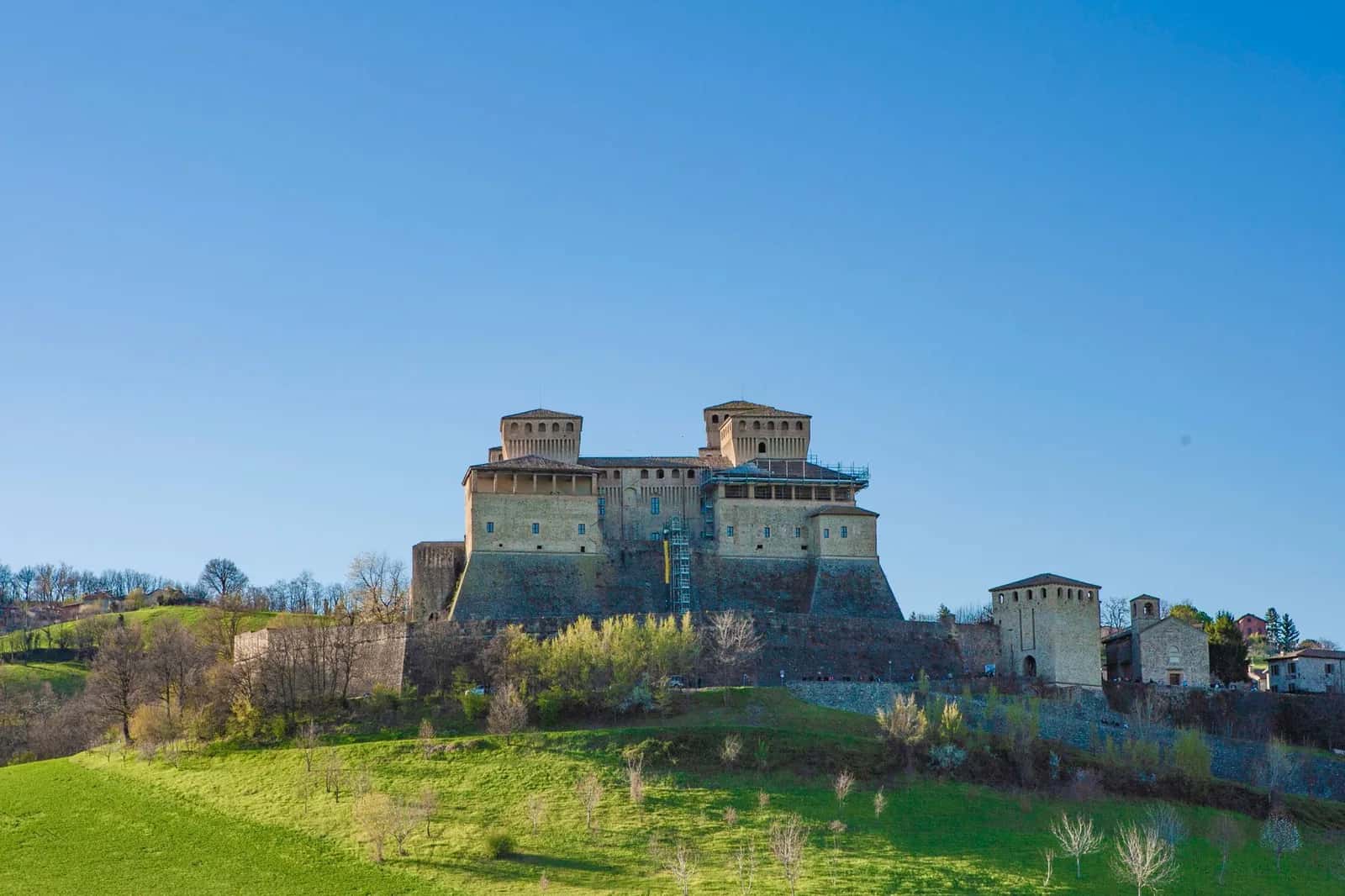 Le château de Torrechiara et ses tours crénelées sur une colline verte de la province de Parme