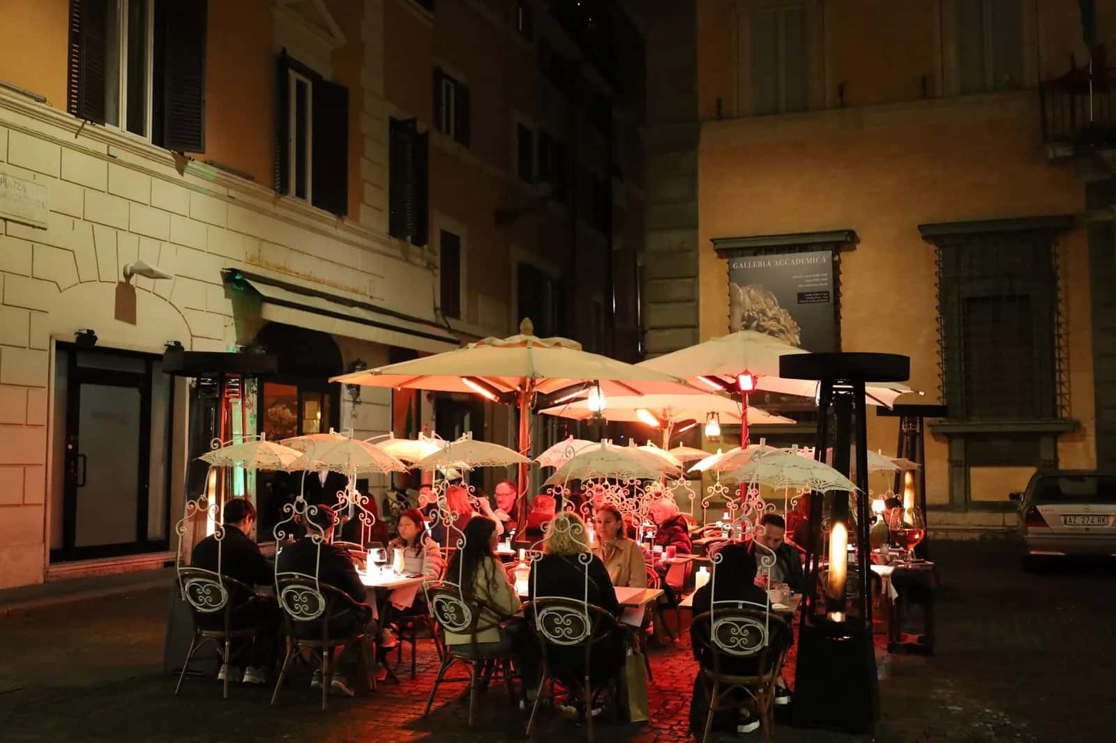 Terrasse de trattoria éclairée le soir dans une ruelle pavée de Rome