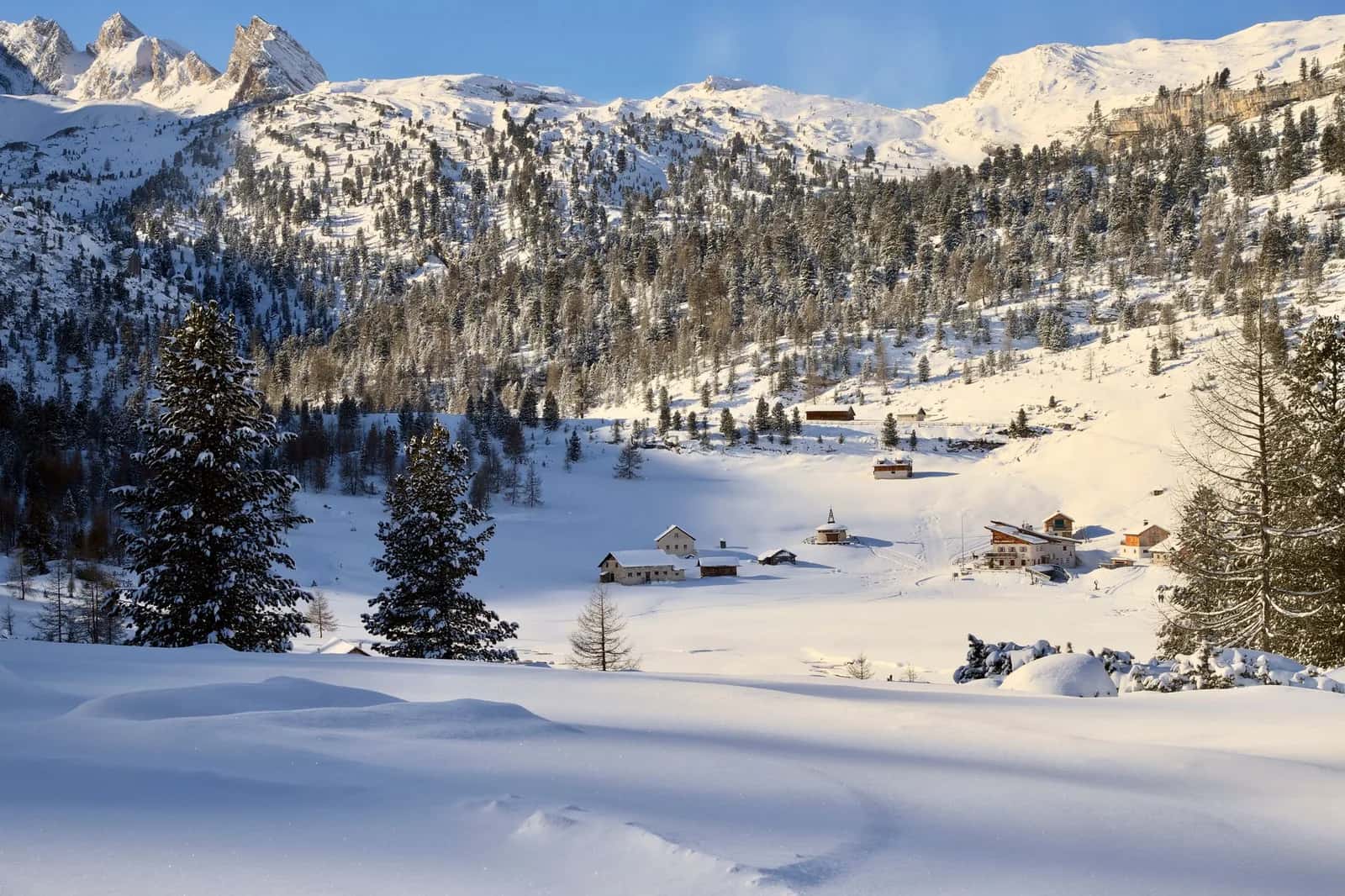 Hameau de granges et chalets sous la neige dans un vallon des Dolomites