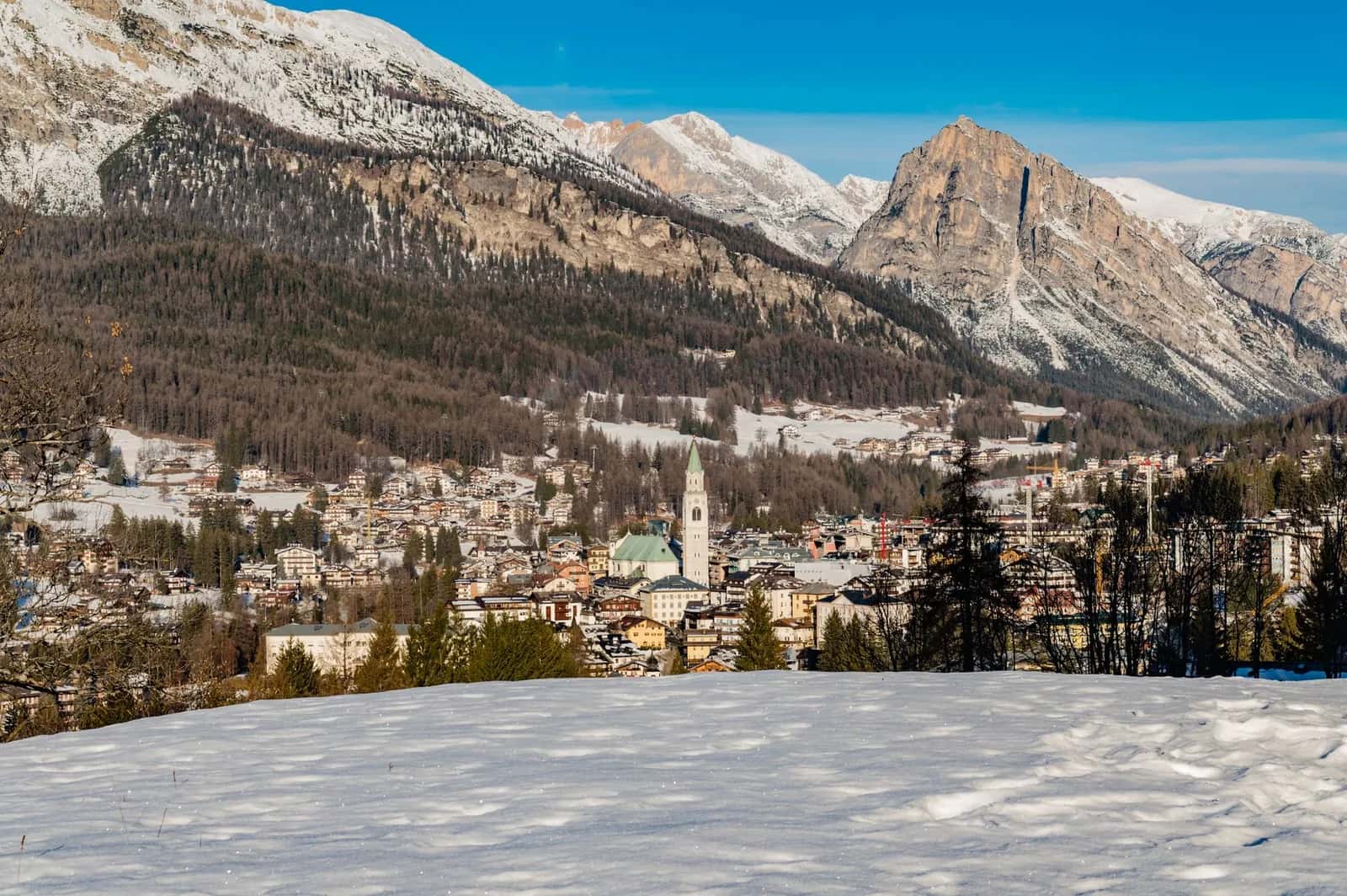 Cortina d'Ampezzo en hiver, village et clocher au pied des montagnes enneigées des Dolomites