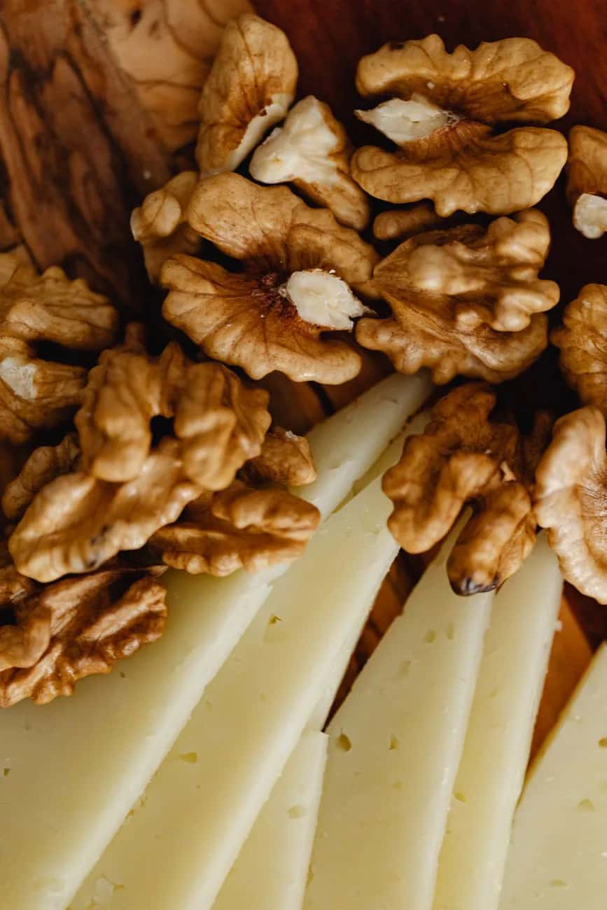 Tranches de pecorino de brebis affiné servies avec des cerneaux de noix sur une planche en bois, à la sarde