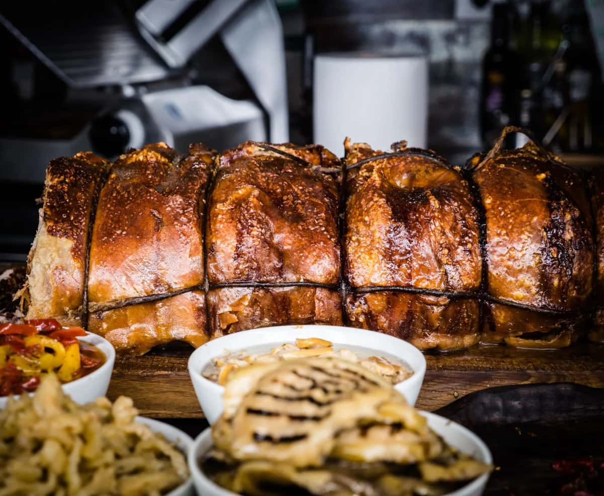 Cochon de lait rôti à la peau croustillante servi avec des accompagnements, à la façon du porceddu sarde