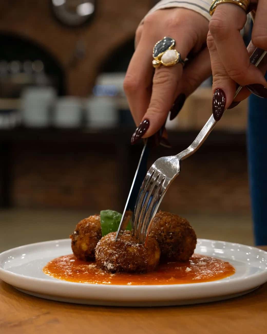 Arancini siciliens panés et frits servis sur un lit de sauce tomate avec du basilic