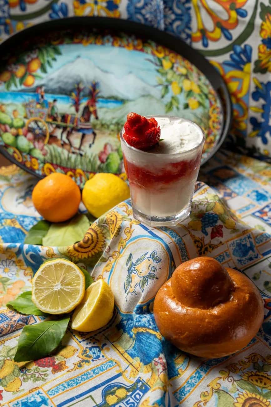 Granita sicilienne servie en verre avec une brioche col tuppo, agrumes et céramique de Sicile