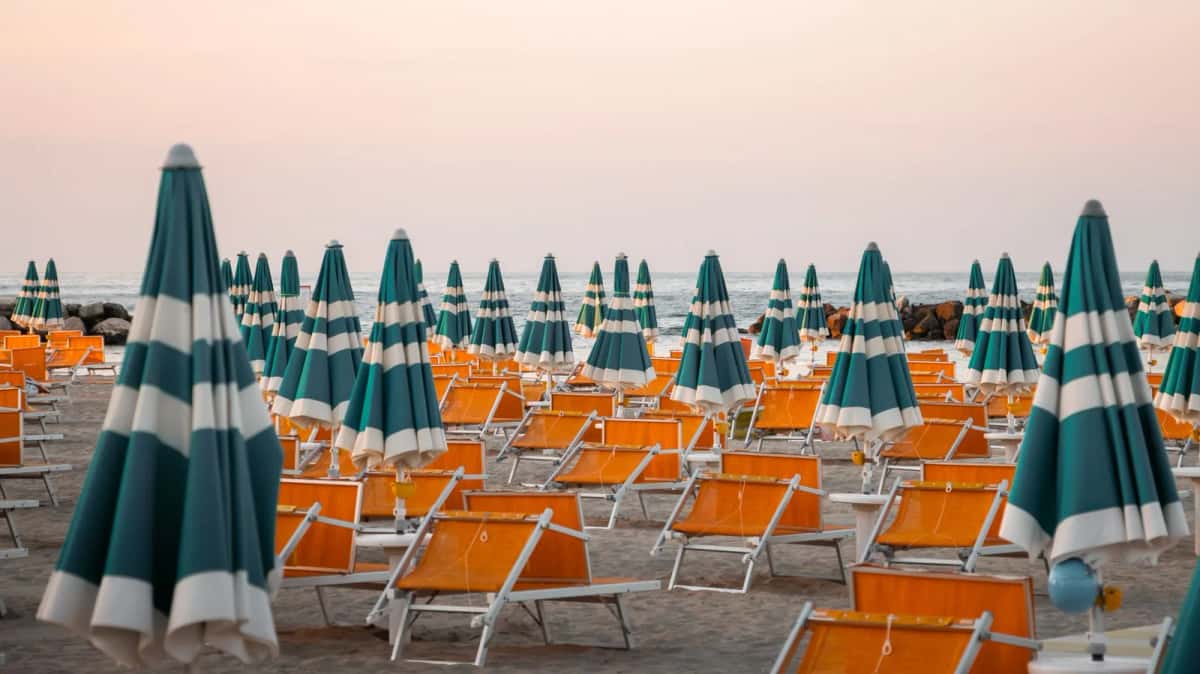 Rangées de parasols rayés et de transats orange sur la plage de Rimini, sur la côte adriatique italienne