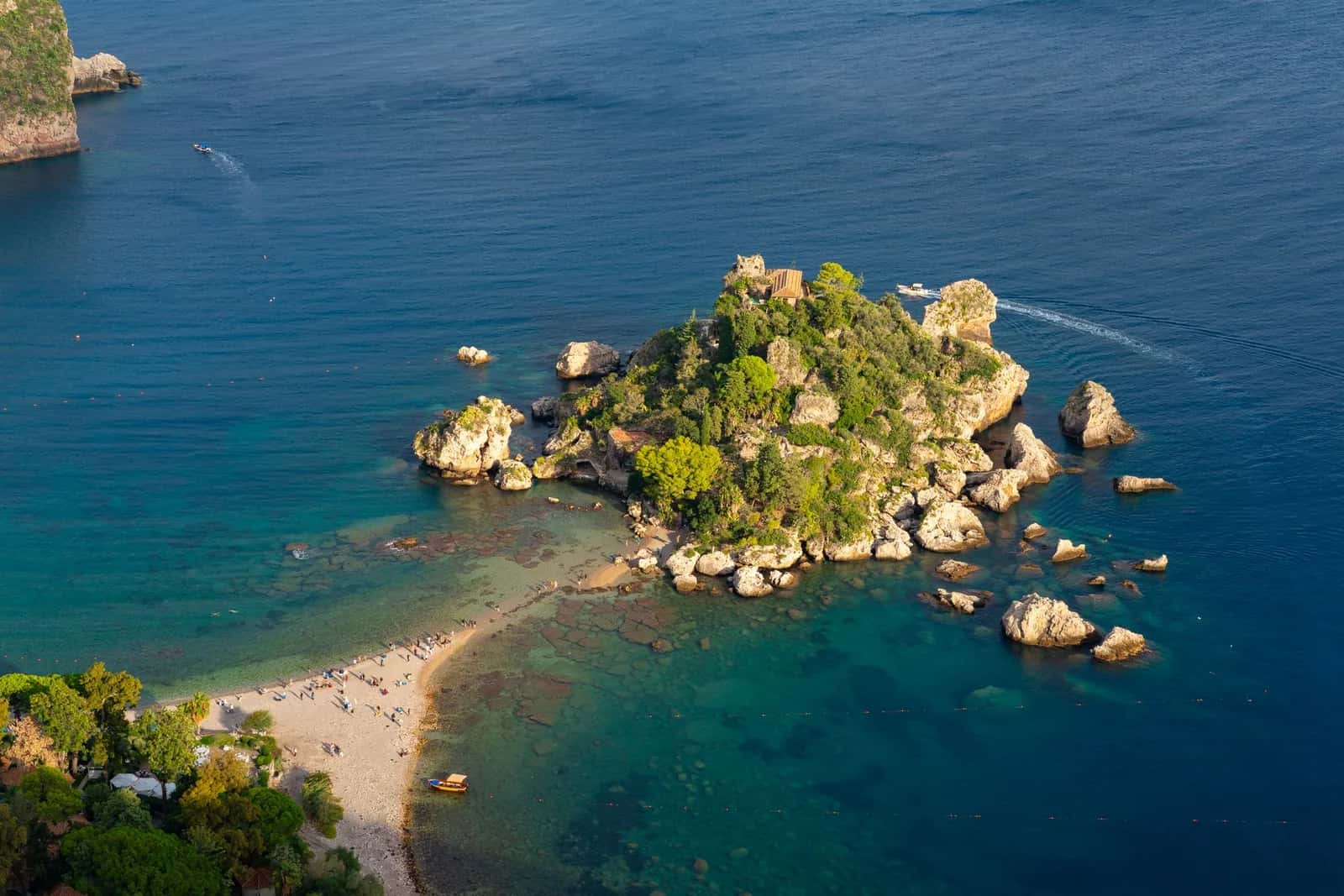 Vue plongeante sur l'îlot boisé d'Isola Bella et son isthme de galets, dans une eau turquoise à Taormine
