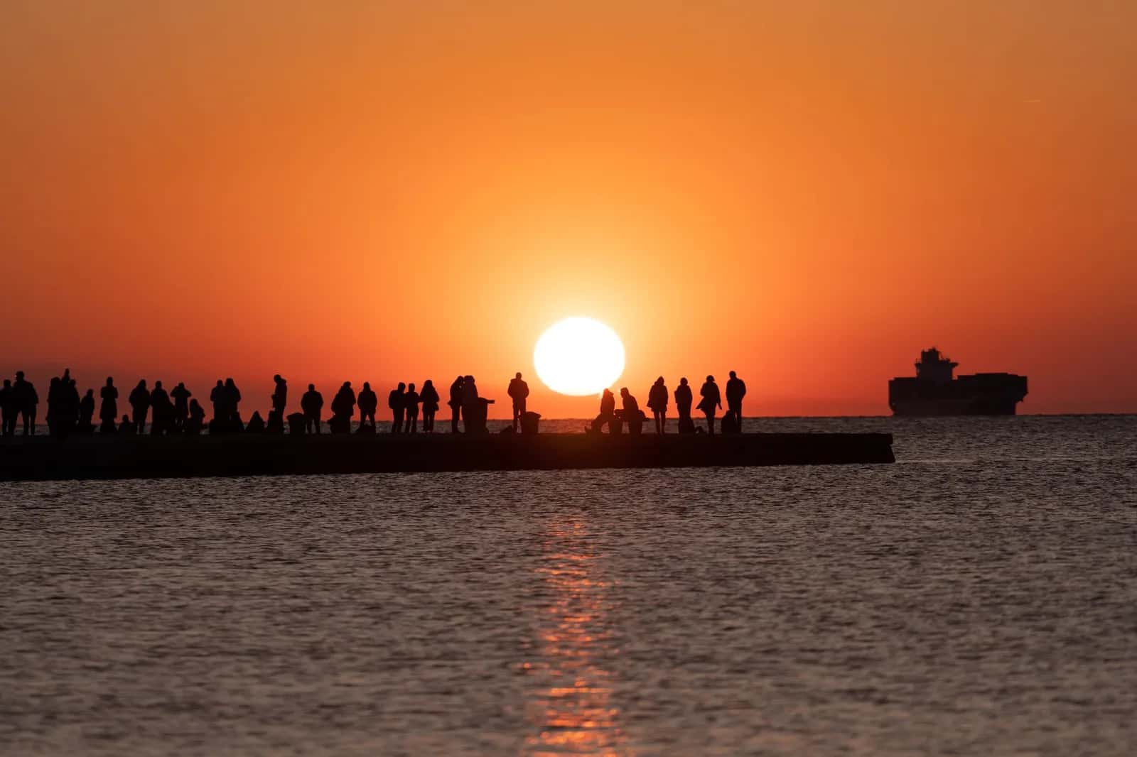 Silhouettes sur une jetée du front de mer de Trieste au coucher du soleil