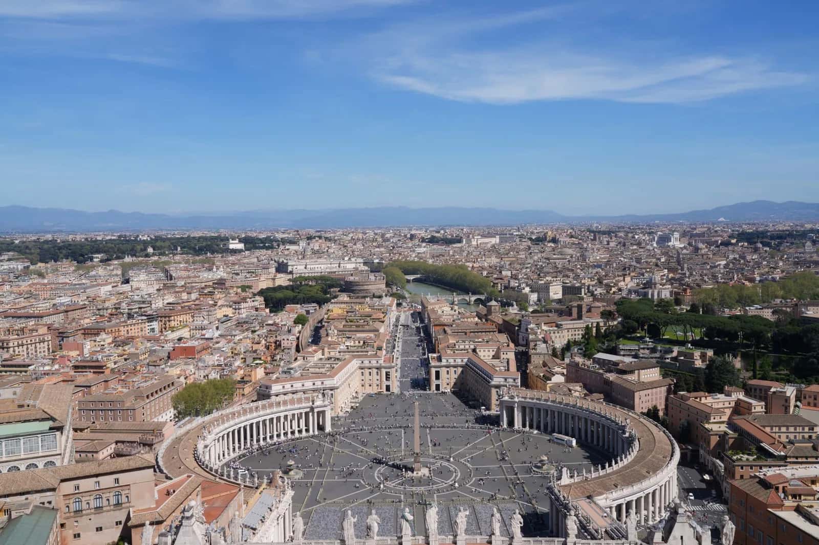 La place Saint-Pierre et la colonnade du Bernin vues du sommet de la coupole, avec le Tibre et le château Saint-Ange au fond, au Vatican