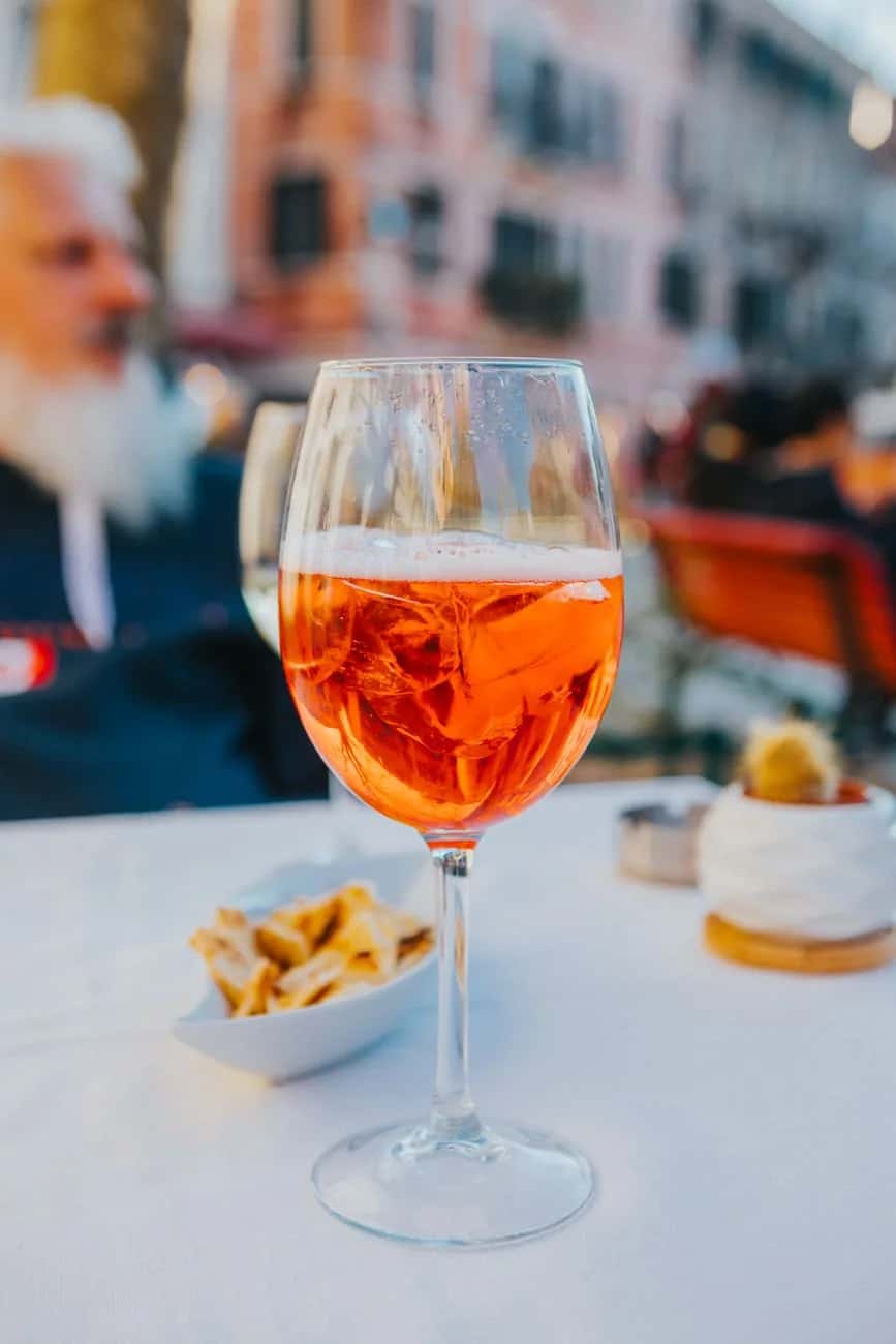 Verre de spritz servi en terrasse avec des amuse-bouches, apéritif emblématique de la Vénétie