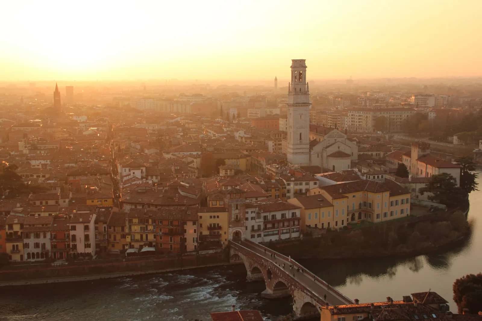 Le Ponte Pietra enjambe l'Adige, avec les toits de Vérone et la tour du Duomo au coucher du soleil